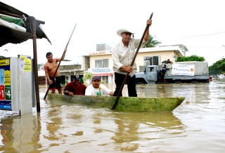 Cuatro hombres en una canoa navegan por una calle inundada a causa del desbordamiento de los ríos Carrizal y Grijalva en Villahermosa, Tabasco.(EFE)