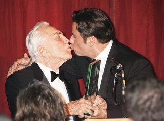 Travolta estampa un beso en los labios a Douglas durante la entrega de un premio honorífico. (AP)