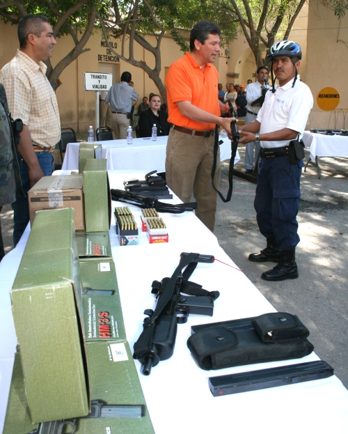 Carlos Aguilera Andrade, alcalde de Ciudad Lerdo, entrega una de las subametralladoras a uno de los agentes preventivos.