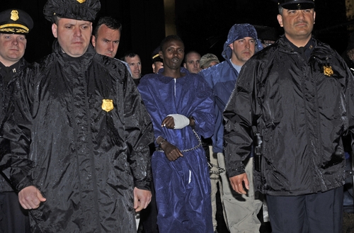 En prisión. La Policía y agentes de Brigada de Investigación Criminal escoltan al sospechoso pirata somalí Abdiwali Abdiqadir Muse en la oficina central de Brigada de Investigación Criminal en Nueva York el pasado 20 de abril. Muse es el pirata sobreviviviente en la toma de rehén de capitán de barco comercial Richard Phillips, el Alabama Maersk.