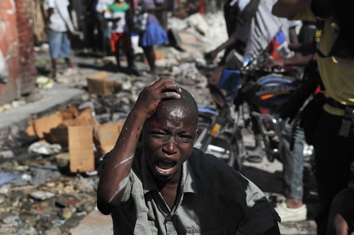 Violencia. Un niño haitiano llora luego de recibir un golpe tras una riña que se suscitó por el saqueo de bienes y víveres en el centro de Puerto Príncipe.