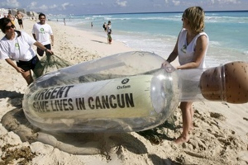 Salven vidas en Cancún. Activistas con un mensaje embotellado en en la playa, precio a la cumbre climática..