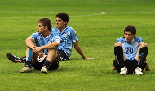 Desconsolados, los seleccionados uruguayos, presenciaban la celebración del equipo mexicano tras ganar el título. (Jam Media)