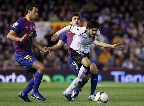El argentino del Valencia Ever Bánega disputa un balón a los jugadores del Barcelona Sergio Busquets (i) y Cesc Fábregas (detrás) durante el partido de ida en el estadio de Mestalla, que terminó empatado a un gol. (EFE)