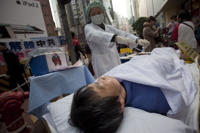 Tráfico. Miembros del grupo religioso Falun Gong vestidos de cirujano y paciente protestan en contra del tráfico de órganos en China.