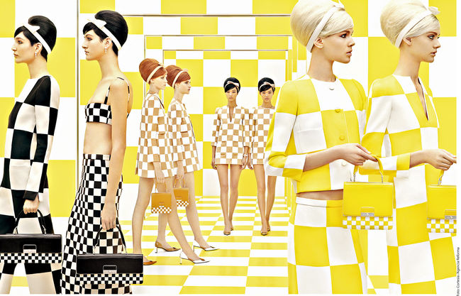 Un gran tablero de damas o ajedrez, reúne a las 12 modelos prometedoras que aparecen vistiendo similares vestidos, así como peinados y carteras idénticas.