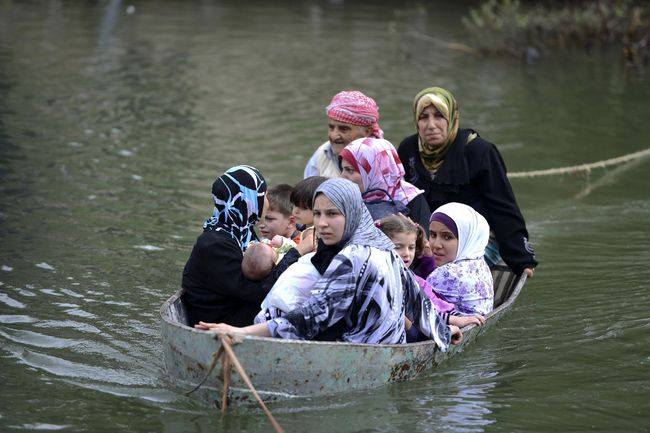 Ayuda humanitaria. Refugiados sirios cruzan en barca hacia Turquía a través del río Orontes, en la frontera siria con Turquía.