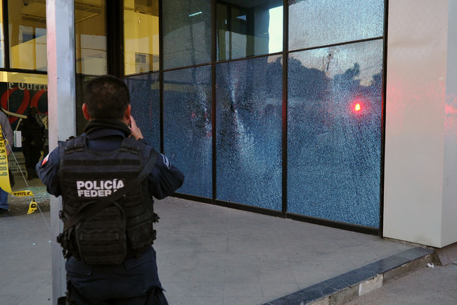 Ataque. Las balas quebraron los cristales en la entrada al edificio.