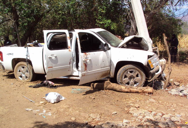 Evidencias. Policías federales custodian un vehículo donde yacen varios cadáveres en la comunidad de Los Girasoles, en Michoacán.