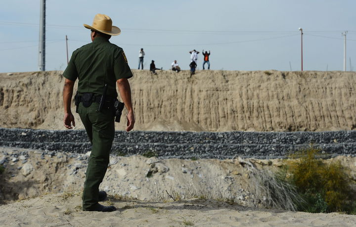 Riesgo. Un agente de la patrulla fronteriza  observa desde territorio estadounidense a un grupo de personas, de pie en el lado mexicano, que intentan cruzar la línea divisoria cerca de McAllen, Texas.