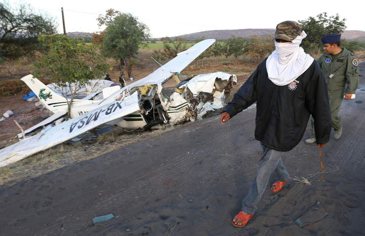 Accidente. Un miembro de un grupo de autodefensas y un militar observan la avioneta accidentada.
