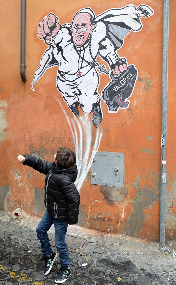 En la pared ubicada en la esquina de las calles Plauto y Borgo Pío, apareció el martes la caricatura del “súper Papa”. (EFE) 