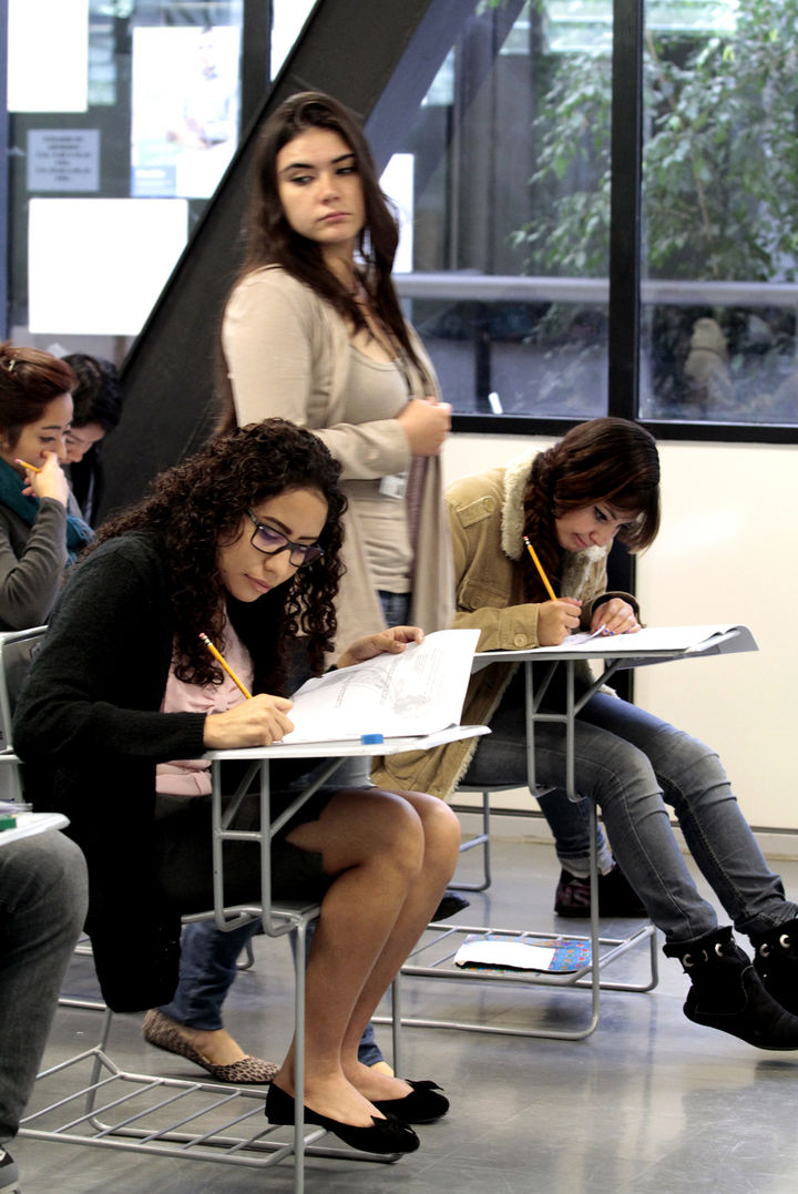 Examen. Una profesora supervisa la aplicación de la prueba a los alumnos de educación media en un aula de clases. 