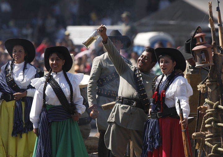 Desfile. Mexicanos participan en la representación de la vida cotidiana de los soldados revolucionarios (1910) en un desfile.