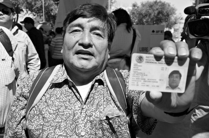 Un hombre muestra su credencial de elector mexicano.