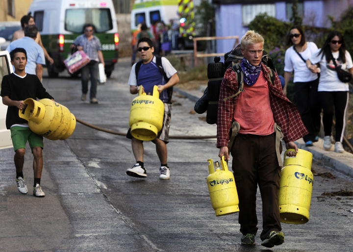 Recipientes. Habitantes llevan recipientes con gas propano de uso doméstico durante su evacuación.