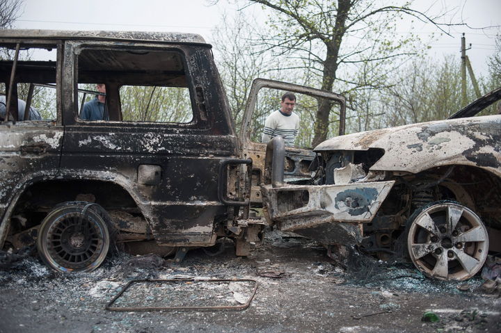 Daños. Hombres observan vehículos quemados frente a un bloqueo prorruso cerca de Slaviansk, Ucrania.