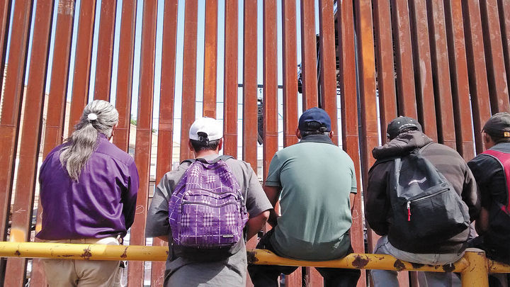 Frontera.  Frente al muro que separa Sonora y Arizona, un grupo de migrantes espera pacientemente una oportunidad para cruzar la frontera.