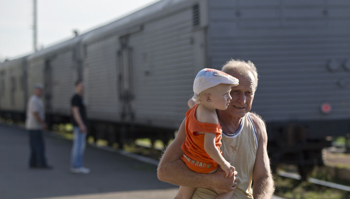 Vagones. Un hombre camina con su nieto tras pasar los vagones en donde están los niños migrantes. (EFE)