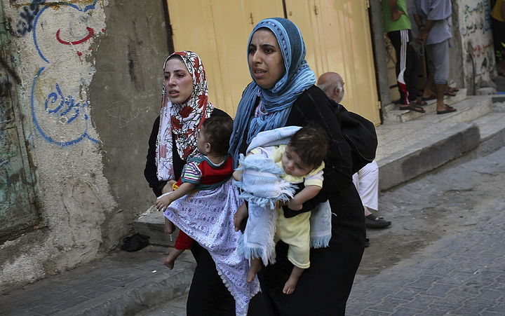 Corren. Dos madres corren con sus hijos en brazos tras el incremento de los ataques. Buscan refugio. (AP)