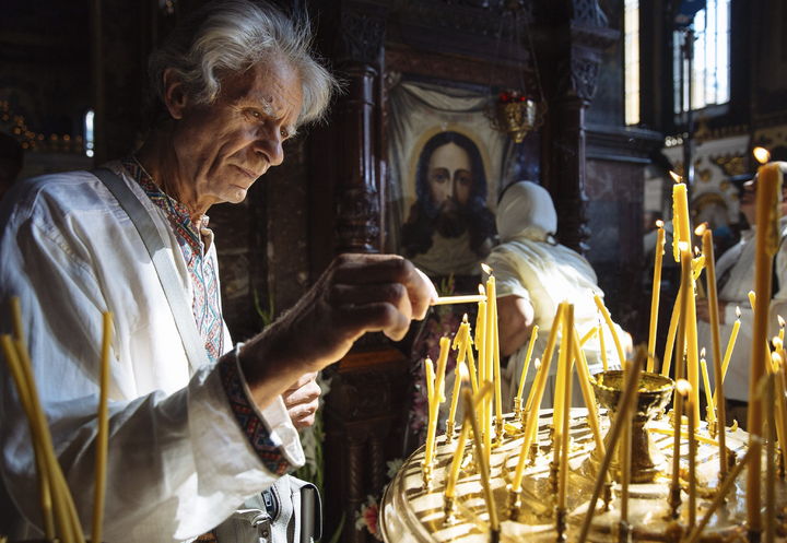 Celebran cristianización.- Un anciano enciende una vela durante una oración de la Iglesia Ortodoxa Ucraniana. (EFE)