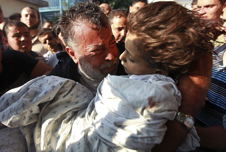 Bombardeos.  El palestino Akram Miqdad llora mientras saca en brazos el cadáver de su hija Bara-a, de seis años. Los palestinos vivieron una noche de tristeza. (EFE)