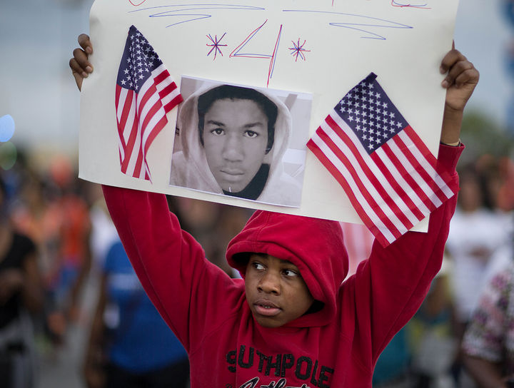 Asesinatos. En la imagen un niño de Atlanta sostiende una pancarta de un joven asesinado igual de Michael Brown.