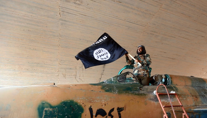 Guerra. Un hombre porta una bandera del Estado Islámico en Siria, mientras EU combate en Irak.