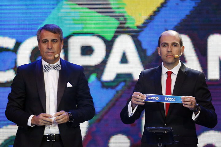 El presidente de la Asociación Nacional de Futbol Profesional de Chile, ANFP, Sergio Jadue (der.), junto al exfutbolista argentino Leonardo Rodríguez (izq.) muestra el nombre de México durante el sorteo de la Copa América. (EFE)