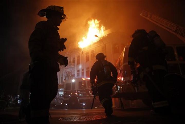Una multitud reunida en la zona contemplaba el miércoles por la noche el humo y las llamas que salían del edificio, de uso mixto. (AP)