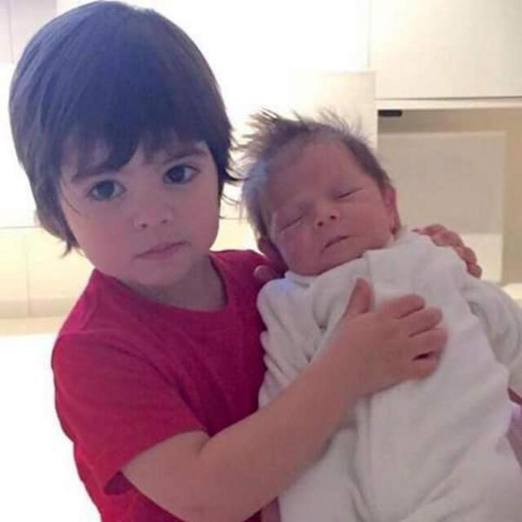 En la imagen, pareciera que Milan sostiene en brazos a su pequeño hermano; sin embargo, si se observa detenidamente, puede verse la mano de un adulto sosteniendo a Sasha. (TWITTER)