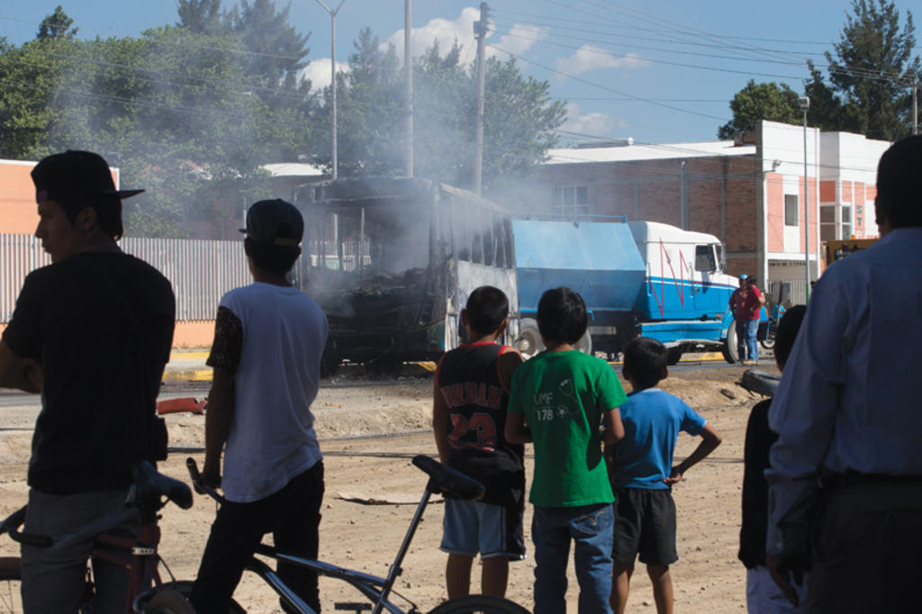 La gente ve un autobús de pasajeros incendiado, después de que el fuego ha sido extinguido por los bomberos en Guadalajara (2015). (Foto: AP)
