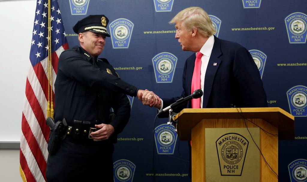 Primarias. Donald Trump saluda a un policía en su mitin de campaña, en donde pidió que se repitan elcción. (EFE)