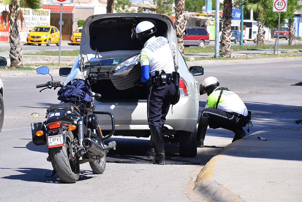 Ayuda. Agentes de Tránsito apoyan a una mujer a cambiar la llanta de su vehículo ponchado ayer en el bulevar La Libertad. (Fernando Compeán)