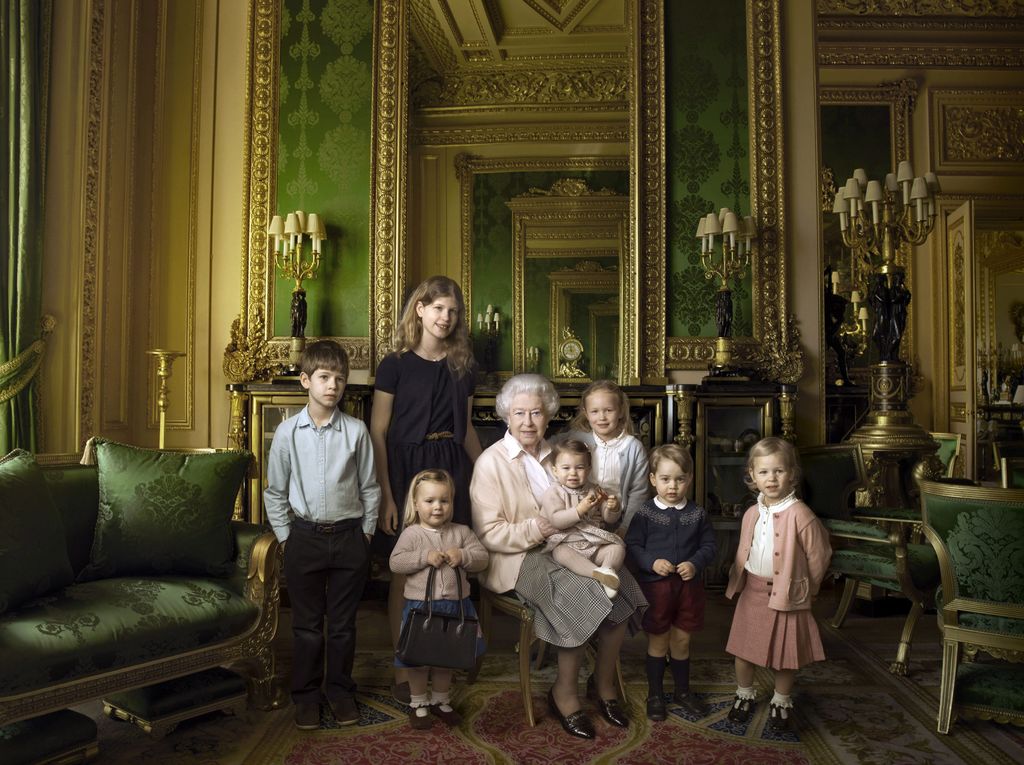 En la instantánea, la monarca sostiene en su regazo a su bisnieta más pequeña, la princesa Carlota, segunda hija del príncipe Guillermo y Catalina, mientras que el príncipe Jorge, el primogénito de los duques de Cambridge, se sitúa a su lado. (EFE)