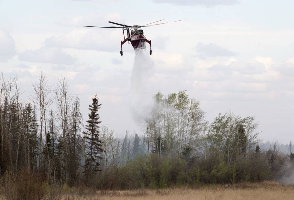 Por aire. Un helicóptero suelta una carga de agua sobre el incendio cerca de la autopista a Fort McMurray, Canadá.