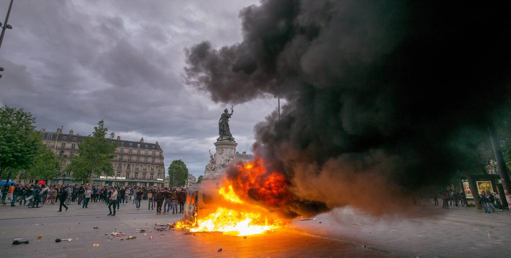 Más protestas.  Un grupo de personas protesta cerca a un vehículo incendiado en la Plaza de la República en París.