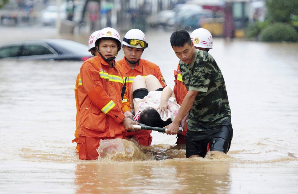 Tragedia.  Varios miembros de los servicios de rescate mientras evacuan a una mujer herida por una calle inundada. 