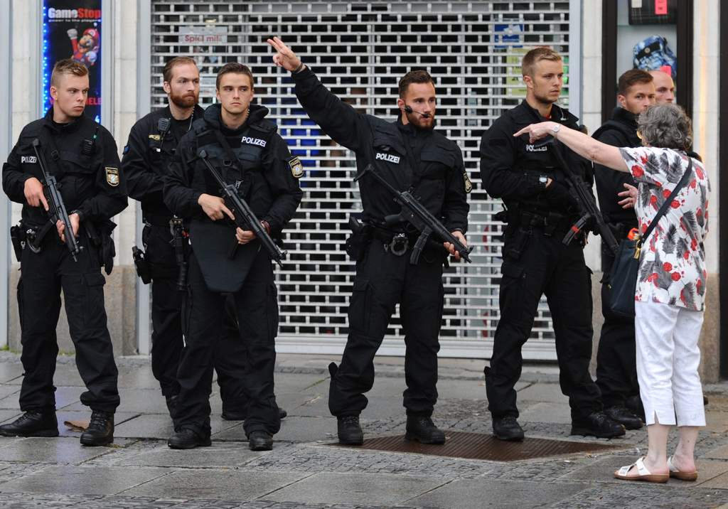 Tensión. Policías fuertemente armados dan instrucciones a una mujer en el cerco de seguridad instalado luego del ataque a balazos perpetrado por un joven en el centro comercial Olympia, en la ciudad de Múnich, capital de Baviera. (EFE)