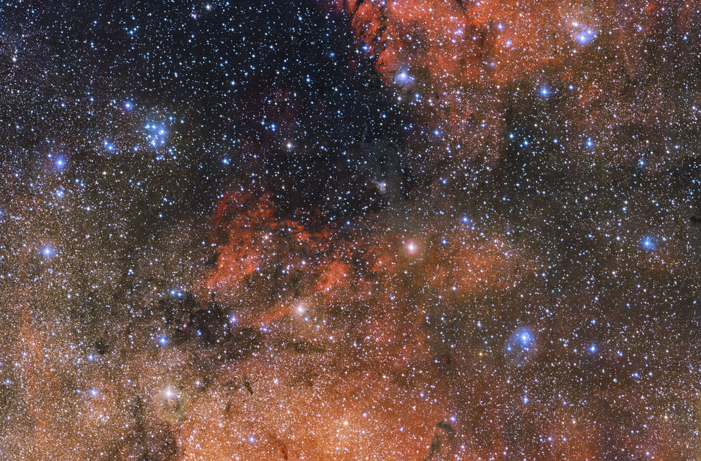 Muestra un puñado de llamativas estrellas azules y nubes rojas de hidrógeno ionizado brillante y oscuros filamentos de polvo. (EFE)