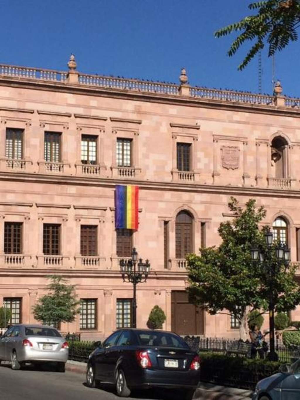 A un costado del balcón central pende la bandera multicolor en posición vertical que se colocarán a partir de este lunes en edificios públicos de toda la entidad. (ESPECIAL) 