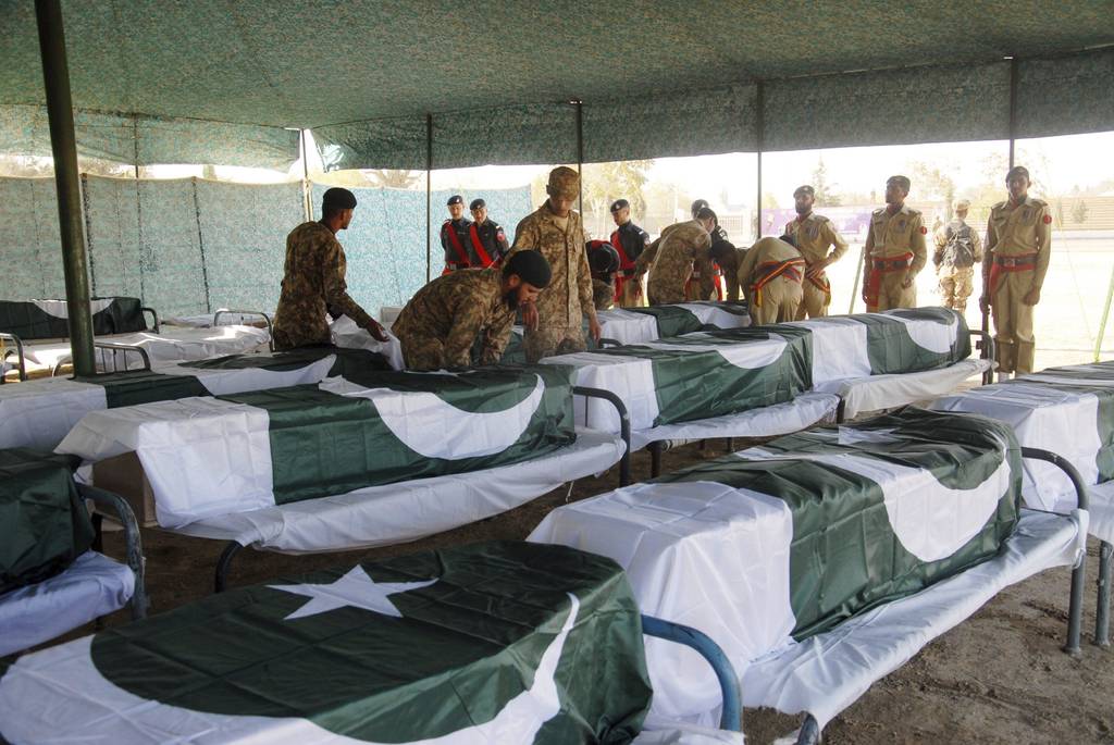 Luto. Soldados paquistaníes permanecen junto a los féretros de algunas de las víctimas de la matanza en una academia de policía.