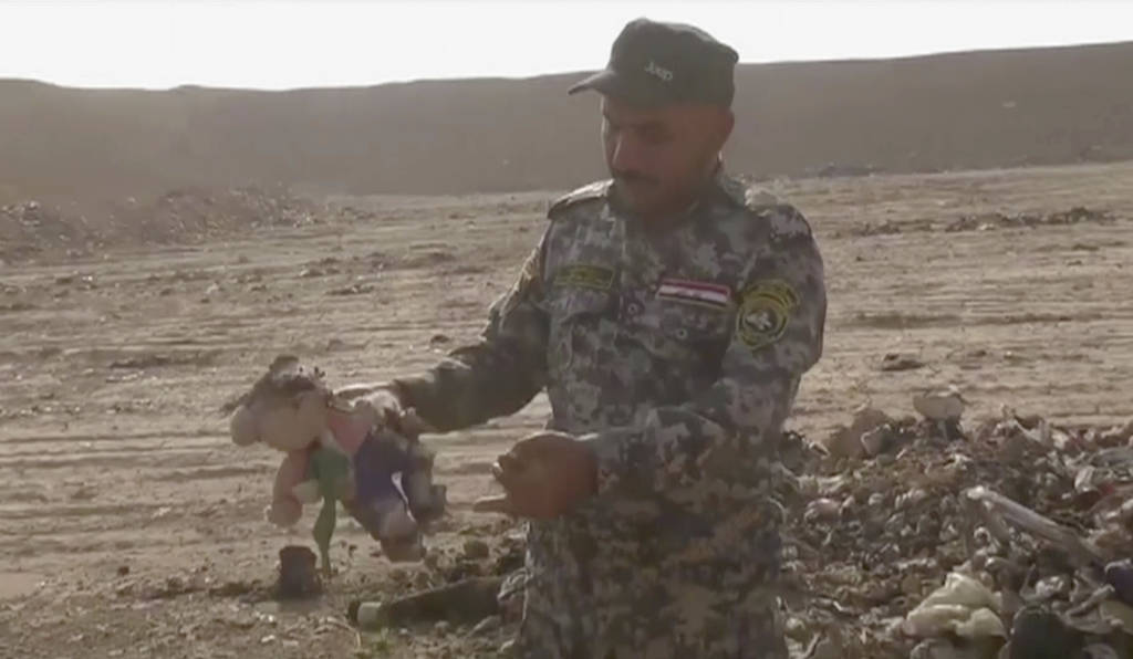 Hallazgo. Un militar iraquí sostiene un muñeco de peluche encontrado junto a los restos de cientos de personas en una fosa. 