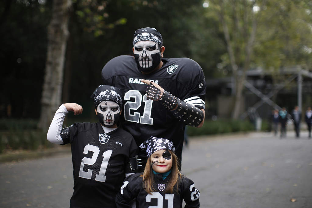 Una familia aficionada a los Raiders posa para la foto en el Fan Fest de la Ciudad de México. (AP)