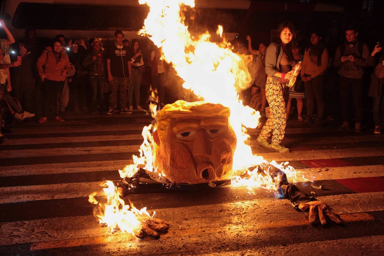 A palos. Manifestantes en la Ciudad de México, le prendieron fuego a una piñata de Trump. (EFE)