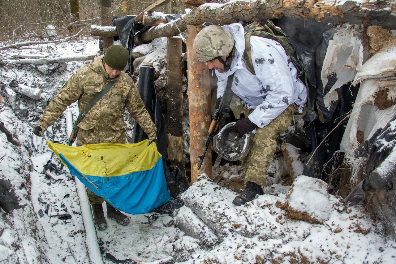 Conflicto.  Militares extraen una bandera ucraniana de la nieve en una calle de Donetsk.