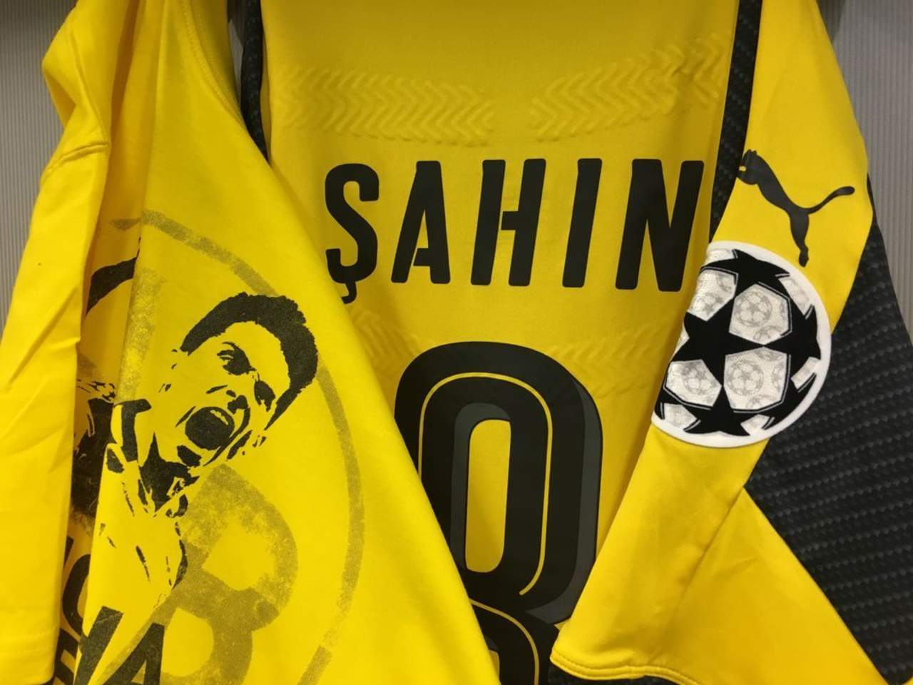 La camisa, con el clásico color amarillo, se puede leer 'Mucha fuerza, estamos contigo' junto a una imagen del jugador.