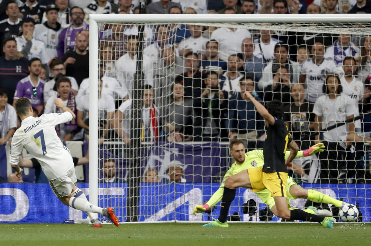 El delantero portugués del Real Madrid Cristiano Ronaldo (i) lanza a puerta para marcar su tercer gol ante el Atlético de Madrid. (Notimex)
