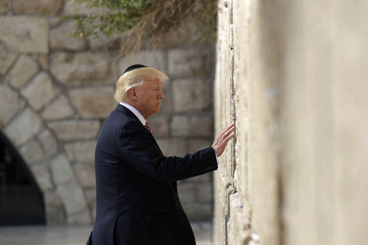 En el Muro, Trump, con la cabeza cubierta como es preceptivo por una kipá (solideo judío), rezó unos instantes mientras tocaba las grandes piedras y, siguiendo la tradición, depositó en los intersticios un papel con una petición. (ARCHIVO)
