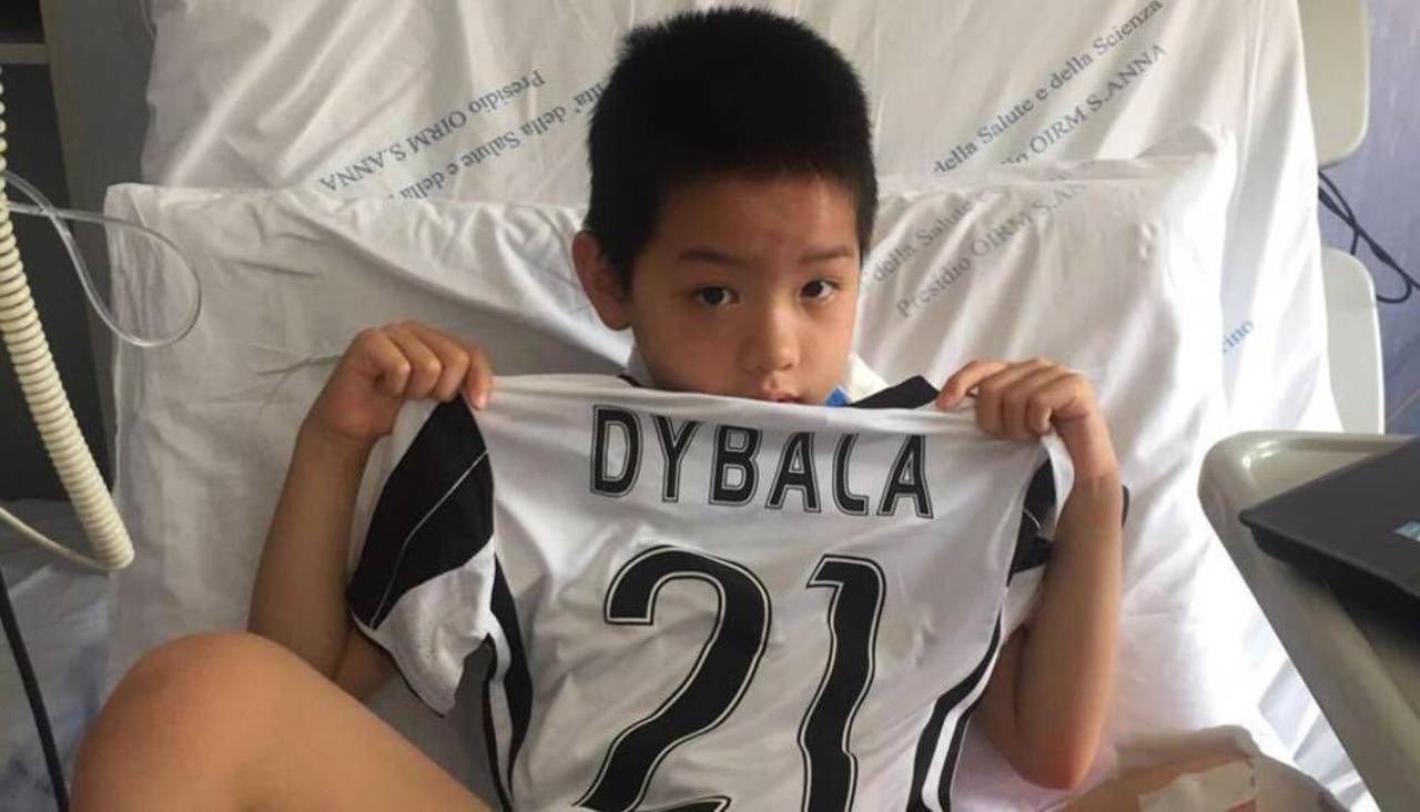 El pequeño aficionado al futbol muestra el regalo del jugador de la Juventus. Dybala da su playera a un niño herido